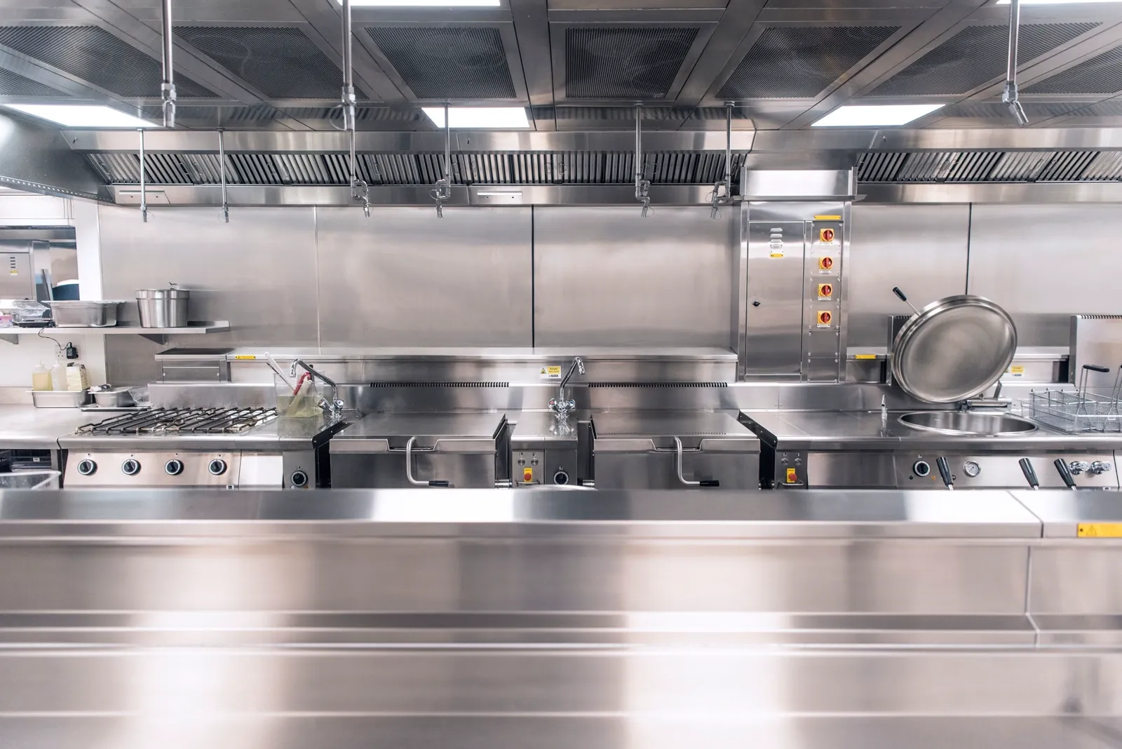 Cucina professionale in acciaio inox con linea di cottura e cappa